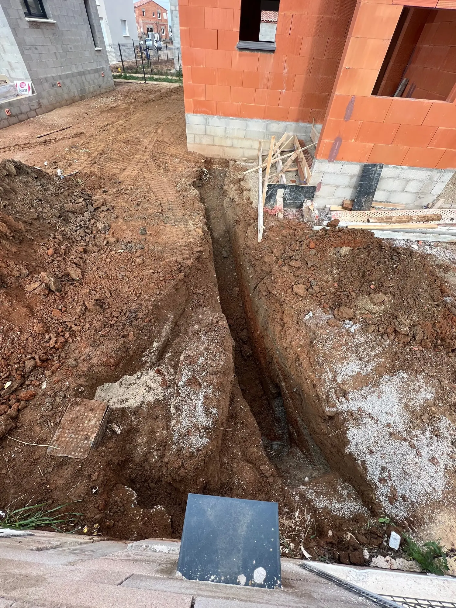 Tranchée profonde ouverte à la minipelle entre deux villas en construction