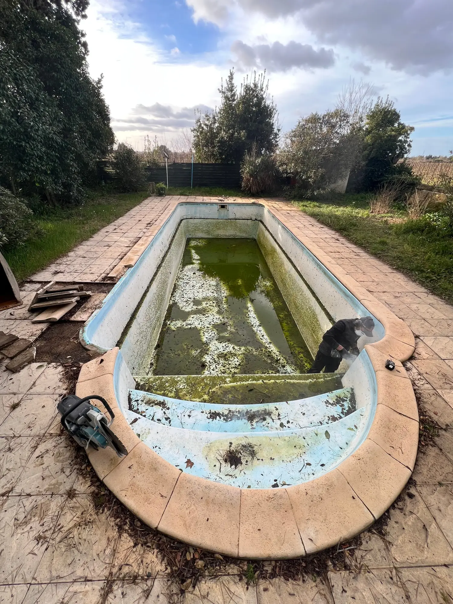 Ancien bassin en pierre avant démolition, rempli d’eau stagnante
