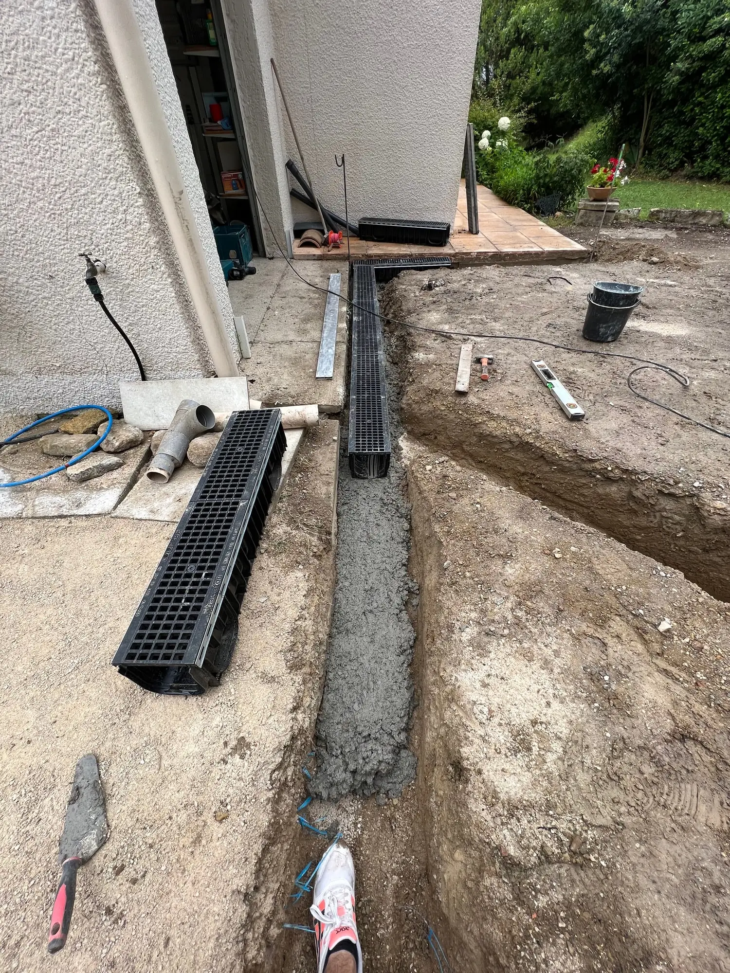 Caniveau à grille mis en place et calé au béton avant remblaiement