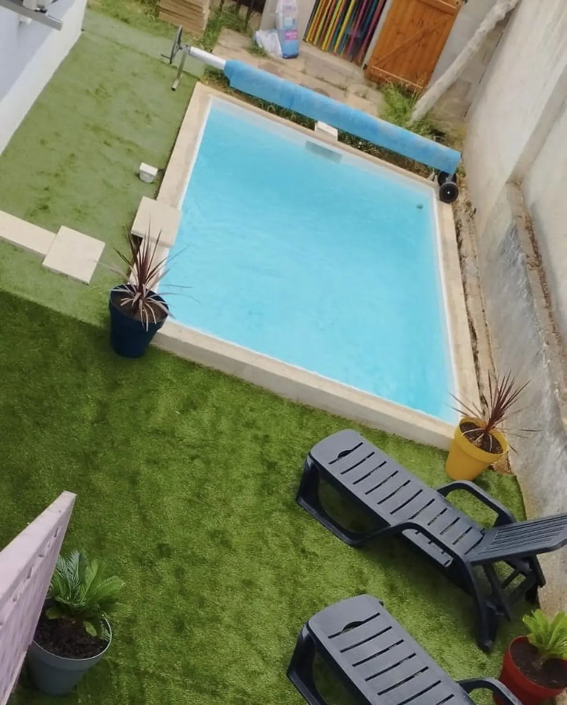 Le même jardin une fois la piscine terminée, margelles claires, gazon et transats