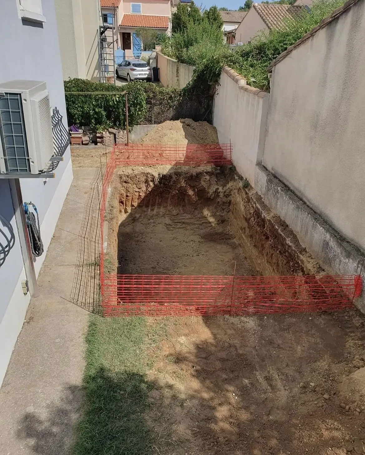Fouille du bassin creusée sur toute la largeur du jardin, ferraillage en attente et zone balisée